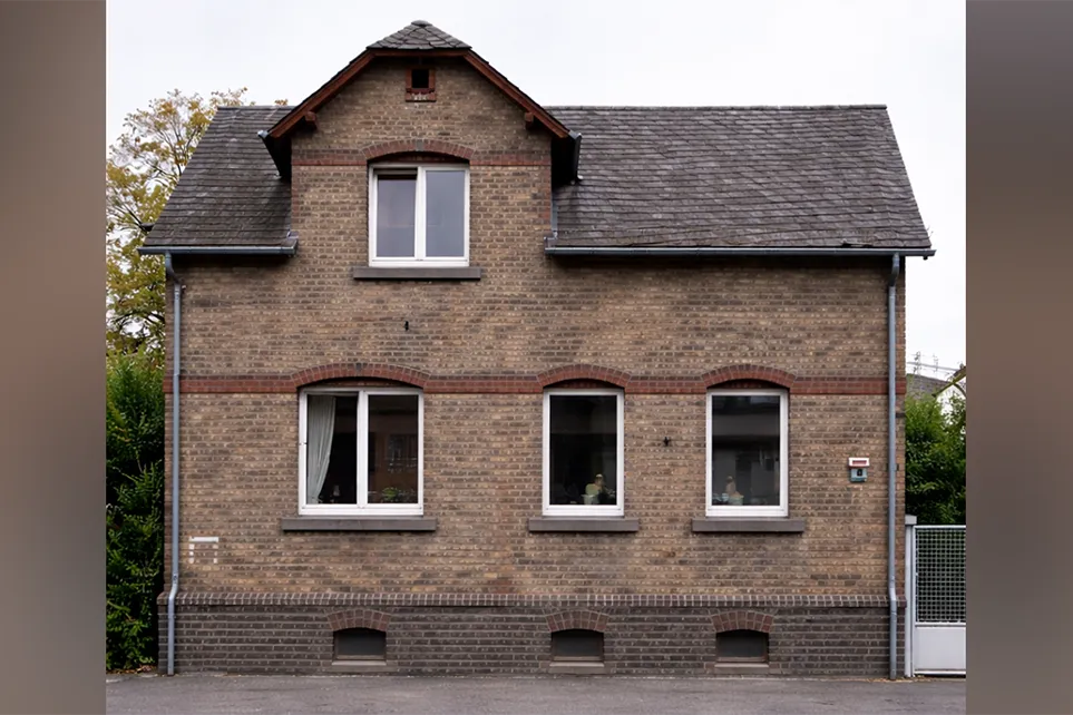 Ein renovierungsbedürftiges Haus mit dunklen Backsteinen.