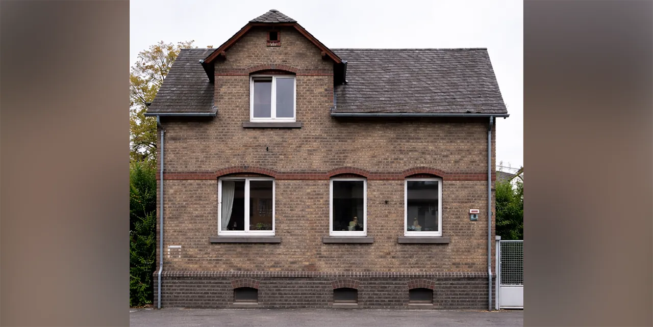Ein renovierungsbedürftiges Haus mit dunklen Backsteinen.